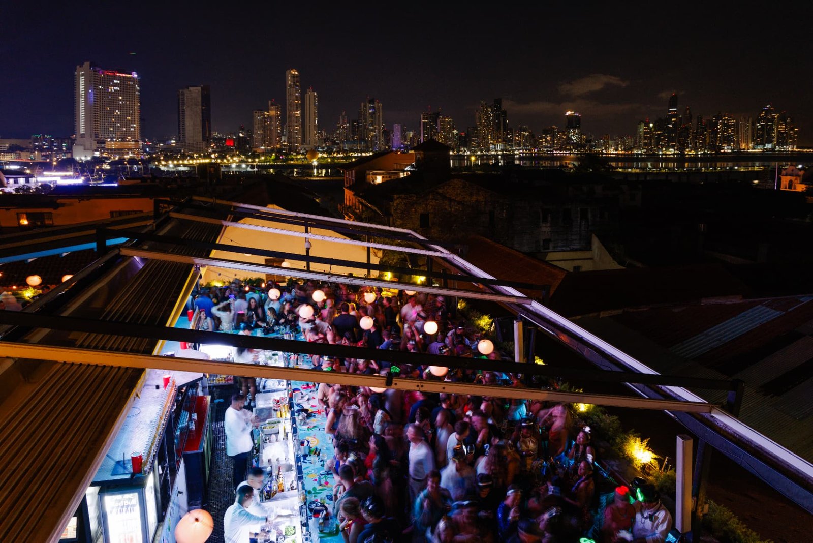 Vista aérea nocturna del rooftop bar de Tántalo Hotel lleno de gente, con el skyline de Ciudad de Panamá al fondo