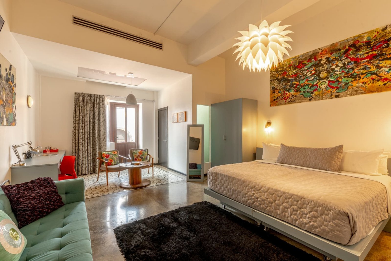 Habitación Double Double con sofá turquesa y cama king, intervenida por el artista Cris Allende